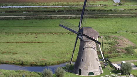 Drone-fly-by-iconic-rural-Dutch-windmill-zooming-in-on-black-metal-blades