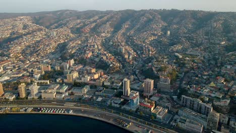 Aerial-dolly-in-of-picturesque-Valparaiso-hillside-city-buildings-and-sea-coastline-at-golden-hour,-Chile
