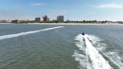 An-aerial-view-over-Gravesend-Bay-in-Brooklyn,-NY-as-two-jet-ski-riders-enjoys-the-day
