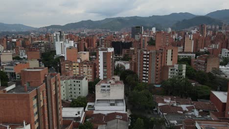 Flying-low-above-buildings-in-a-large-city-in-the-mountains,-Medellin,-Colombia