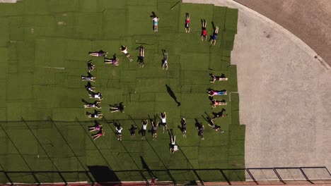 Group-of-kids-lying-on-green-carpet-outdoors-during-physical-education-class
