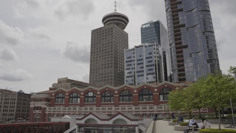 Menschen-Sitzen-In-Der-Nähe-Des-Bahnhofsgebäudes-Am-Wasser,-Des-Harbour-Center-Tower-Und-Der-Wolkenkratzer,-Innenstadt-Von-Vancouver,-Britisch-Kolumbien,-Kanada