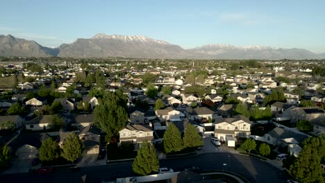 Single-family-homes-in-a-suburban-community-in-a-valley-below-the-Rocky-Mountains---aerial-pullback-view