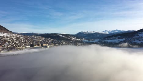 Voss-norway-seen-through-beautiful-morning-haze-on-top-of-frozen-Vangsvatnet-lake---Sideways-moving-aerial