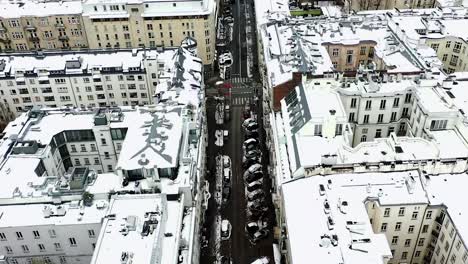 Aerial-view-of-snowy-streets,-revealing-the-skyline-of-Warsaw,-winter-in-Poland---ascending,-tilt,-drone-shot