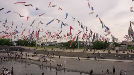 Japanese-People-Gather-at-Park-for-Golden-Week,-Carp-Streamers-Over-River