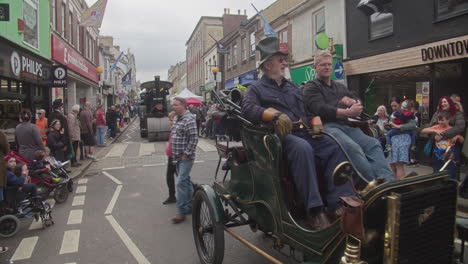 Men-Riding-An-Oldsmobile-Curved-Dash-Followed-By-An-Antique-Steam-Road-Roller-On-The-Street-Of-Camborne