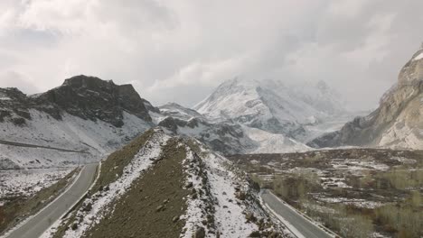 Aerial-Rising-Beside-Empty-Road-To-Reveal-Snow-Covered-Mountain-In-Background-At-Hunza-Valley