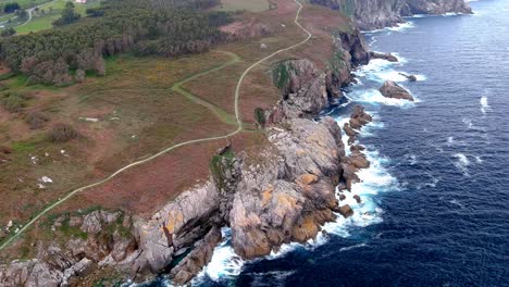 Aerial-drone-shot-of-a-narrow-path-over-an-area-called-paper-cliffs-with-steep-cliffs-in-Morás,-Xove,-Lugo,-Galicia,-Spain-at-daytime