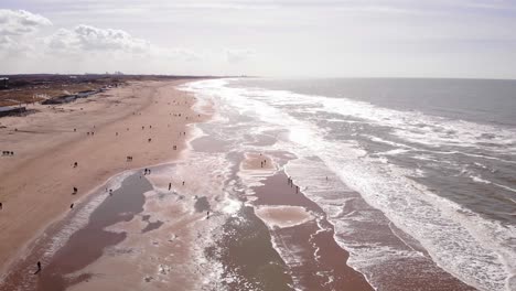 Aerial-Flying-Along-Katwijk-aan-Zee-Beach-Coastline-On-Sunny-Day-With-People-Dotted-Around