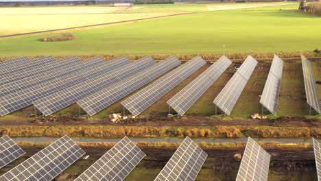 Schwenk-Drohnenaufnahme-Eines-Solarkraftwerks,-Im-Hintergrund-Sonnige-Gras--Und-Weizenfelder