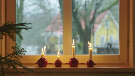 CHRISTMAS-DECORATIONS---Advent-candles-next-to-a-window,-Sweden,-medium-shot