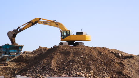 Mechanical-Digger-moving-soil-into-a-sifting-and-reclamation-machine-from-a-large-soil-deposit