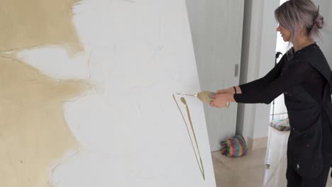 Talented-Female-Artist-Applying-Paint-And-Spreading-With-Paintbrush-On-A-Large-Canvas-Inside-Her-Art-Studio---medium-shot,-slow-motion