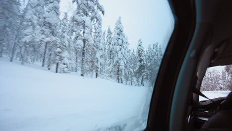 Snowy,-winter-forest,-while-sitting-inside-a-car,-overcast-day,-in-Lapland---POV-shot