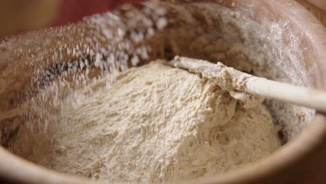 BAKING---Sprinkling-flour-over-batter,-sourdough-bread,-slow-motion-zoom-in