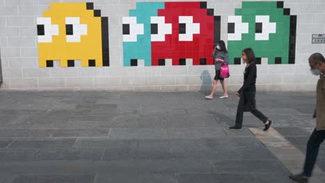 Menschen-Gehen-An-Einem-Wall-Street-Kunstwerk-Vorbei,-Das-Das-Klassische-Arcade-Spiel-Pac-Man-In-Hongkong-Darstellt