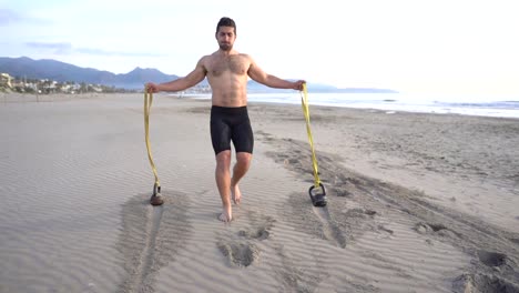 metabolic-workout-on-the-beach-with-muscular-man-performing-back-and-rubber-variant-with-kettlebell-at-sunrise