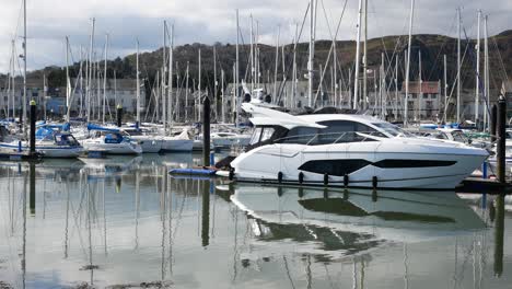 Yachts-and-speedboat-moored-under-luxury-Conwy-mountainous-peaceful-marina-waterfront-North-Wales