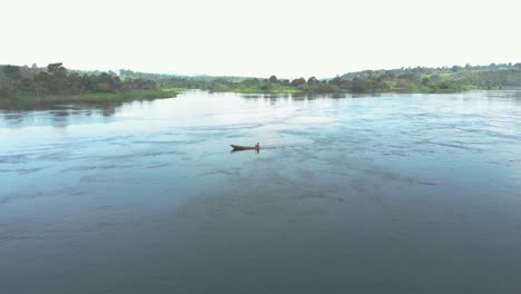 Aerial-orbiting-around-an-African-man-in-a-traditional-fishing-boat-paddling-upstream-on-the-river-Nile