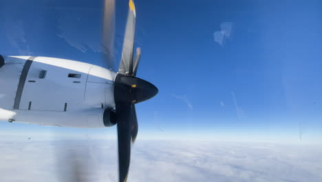 Rotating-propeller-on-a-small-airplane-in-the-air,-clear-blue-sky-with-clouds