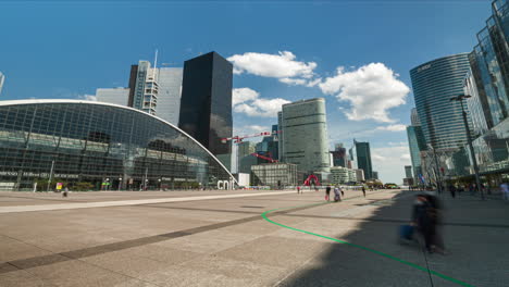 Parvis-of-La-Défense-square-with-CNIT-building-and-people-walking-by-during-sunny-day-wide-angle-time-lapse