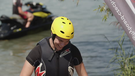 Young-man-with-helmet-and-wetsuit-smiling-into-camera-after-flyboarding-on-sea
