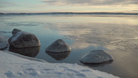 Dramatischer-Sonnenaufgangsblick-Am-Fluss-Mit-Mit-Eis-Bedeckten-Felsen-Während-Der-Wintersaison-In-Finnland