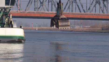 Eintauchen-Einer-Großen-Industrieklaue-Vor-Einer-Eisenbrücke,-Die-Den-Wasserweg-Des-Flusses-Ijssel-Frei-Macht