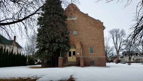 Day-exterior-establishing-shot-of-front-entrance-of-old-abandoned-church-in-the-winter-with-snow