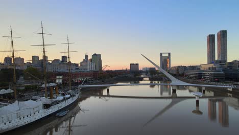 Aerial-dolly-right-of-Sarmiento-frigate-museum-ship-and-Women's-Bridge-in-Puerto-Madero,-Buenos-Aires