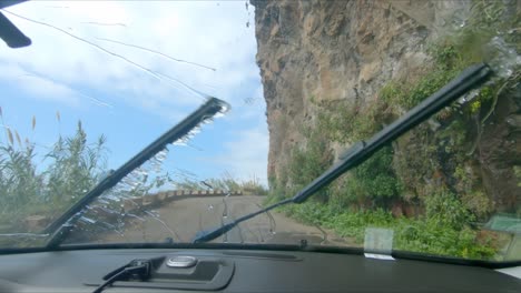 Ein-Auto-Fährt-Unter-Dem-Wasserfall-Ponta-Do-Sol-An-Der-Küste-Der-Insel-Madeira-Hindurch---Wasserfall-Fällt-Auf-Eine-Straße