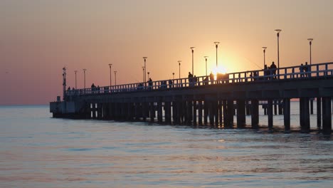 People-Walking-and-Fishing-on-Palanga-Pier-on-Late-Evening-with-Sun-Setting-in-Sky