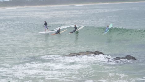 Standup-Paddleboarding---Stand-Up-Paddle-Surf-Montando-Olas-Pasando-A-Otros-Acostados-En-Tablas-De-Surf-En-Scotts-Head,-Nueva-Gales-Del-Sur,-Australia