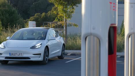 White-Tesla-being-parked-in-a-charging-bay-by-a-business-woman