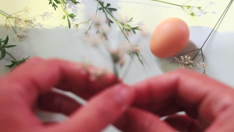 Overhead-view-of-hands-arranging-flowers-and-eggs-to-make-a-Spring-and-Easter-themed-background
