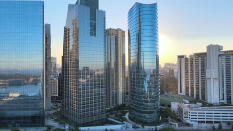 Establishing-aerial-pan-shot-of-a-beam-of-sunlight-through-the-gap-between-shimmering-reflective-glass-facade-skyscrapers-in-downtown-futuristic-central-business-district-of-Buenos-Aires-at-sunset
