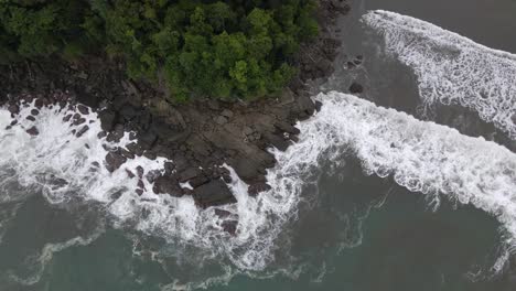 Top-down-aerial-shot-of-strong-sea-waves-crashing-against-rocks-on-the-coast