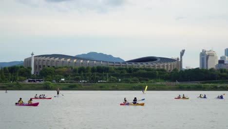 People-Kayaking-At-Han-River-With-Jamsil-Olympic-Stadium-In-Seoul,-South-Korea