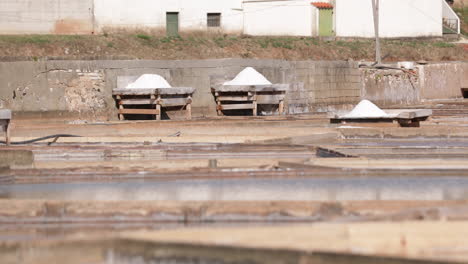 Wooden-Decks-With-Pile-Of-Salt-Drying-On-Sunny-Weather-At-Salinas-De-Rio-Maior-In-Portugal