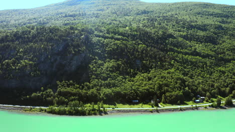 Dickichtiger-Bergwald-An-Der-Küstenstraße-Mit-Autos,-Die-Im-Sommer-Im-Vagavatnet-See,-Norwegen,-Fahren