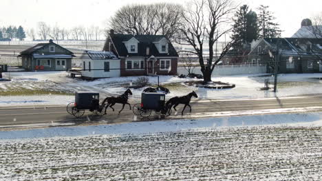 AERIAL-Horse-Drawn-Carriages-Moving-Though-Township-On-Snowy-Winters-Day