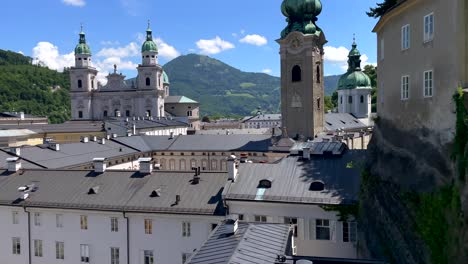 Tilt-up-shot-showing-historical-churches-and-cathedral-in-Salzburg-in-front-of-mountains