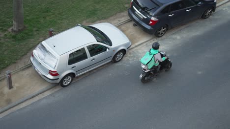Top-down-view-of-Deliveroo-rider-on-a-scooter-underway-to-deliver-the-next-order-at-the-customer