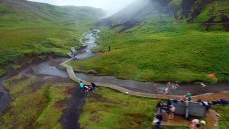 Aerial-flight-over-Reykjadalur-Valley-Steamy-mountain-river-with-people-relaxing-in-the-hot-water---South-Iceland
