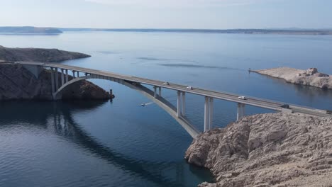 A-row-of-cars-passing-on-concrete-bridge-on-an-island-Pag,-Croatia,-an-aerial-view