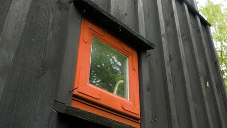 Außenansicht-Eines-Schwarz-Gestrichenen-Alten,-Traditionellen-Hölzernen-Wohnhauses,-Kleines-Rotes-Fenster,-Bewölkter-Tag,-Mittlere-Handaufnahme