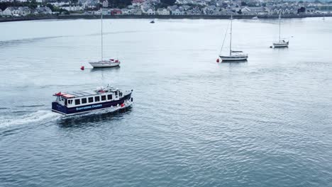 Aerial-view-sightseeing-boat-tourism-attraction-travelling-down-Conwy-river-alongside-seaside-town-North-Wales