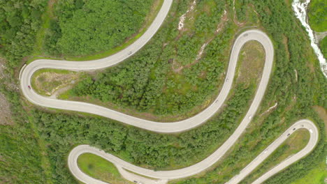 Top-Down-View-Of-Winding-Forest-Road-In-Green-Mountain-Woods-In-Stryn,-Norway---aerial-drone-shot