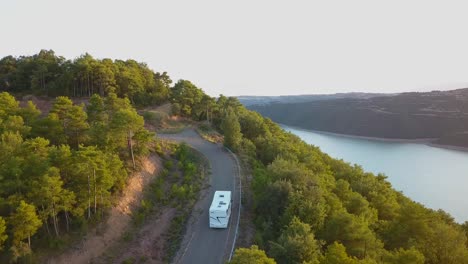Aerial-drone-view-of-a-modern-motorhome-traveling-along-a-lonely-road-in-an-incredible-natural-landscape-at-sunset